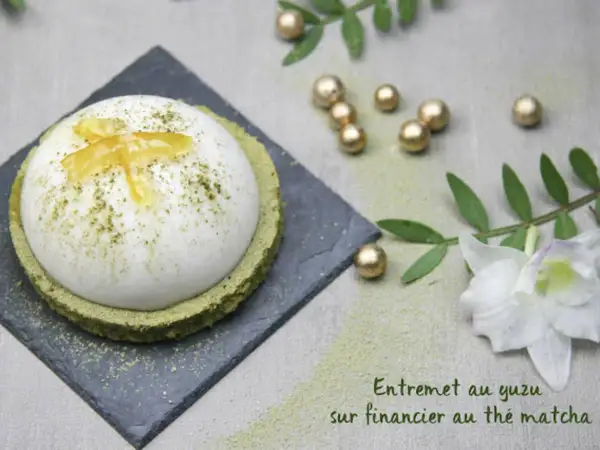 Un entremet yuzu aérien, saupoudré de matcha, repose sur un financier au thé matcha. Décoré de zestes de yuzu confits.