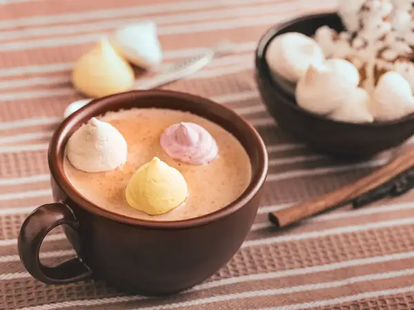Chocolat chaud au lait d'amande, garni de meringues colorées. Un délice réconfortant.