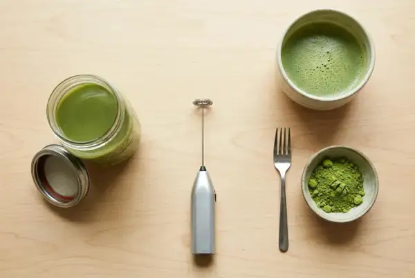 Préparation du matcha sans fouet : poudre verte, boisson mousseuse dans un bol, et un petit appareil argenté pour mélanger.